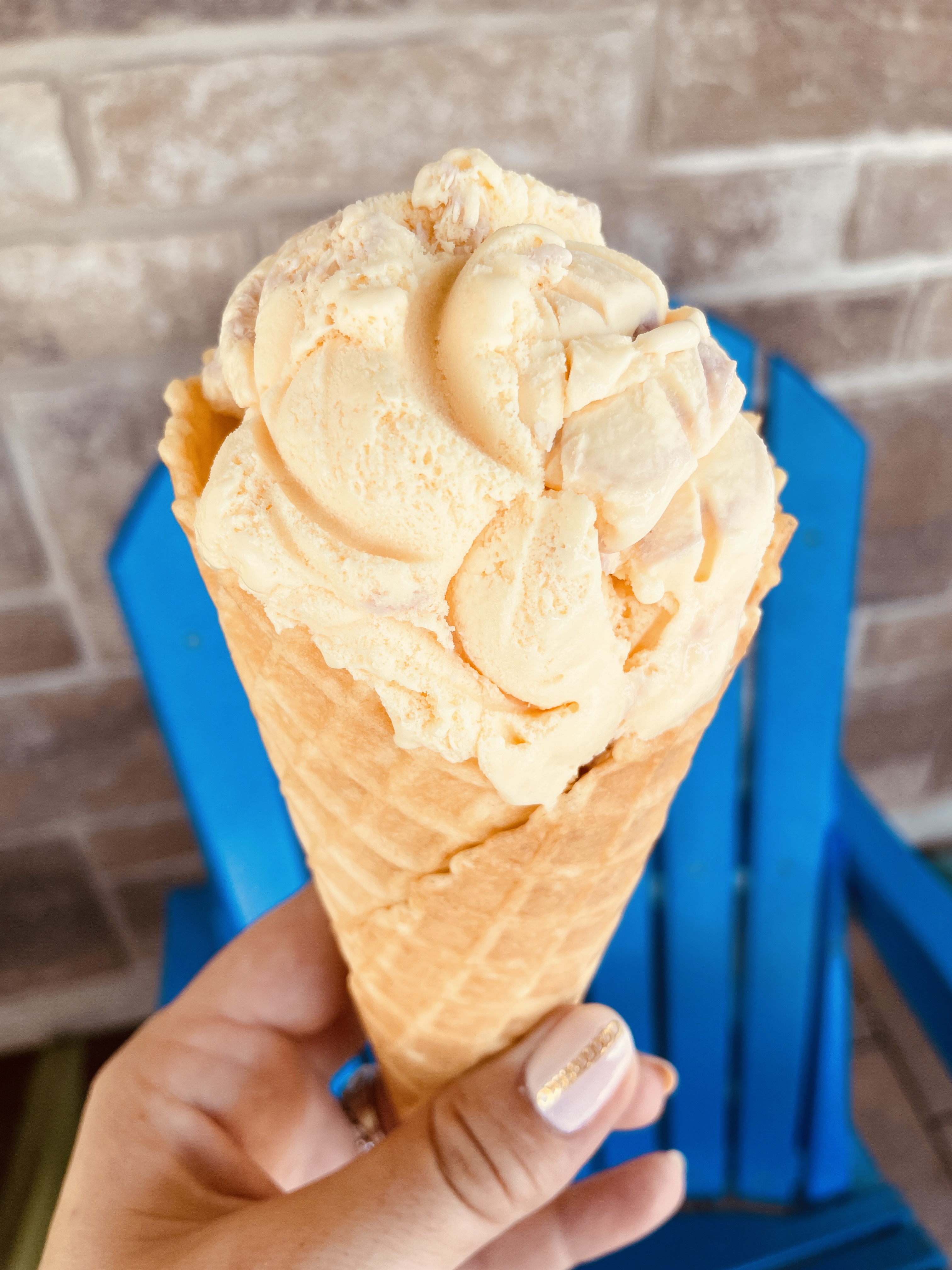 Hand holding a waffle cone filled with vanilla ice cream